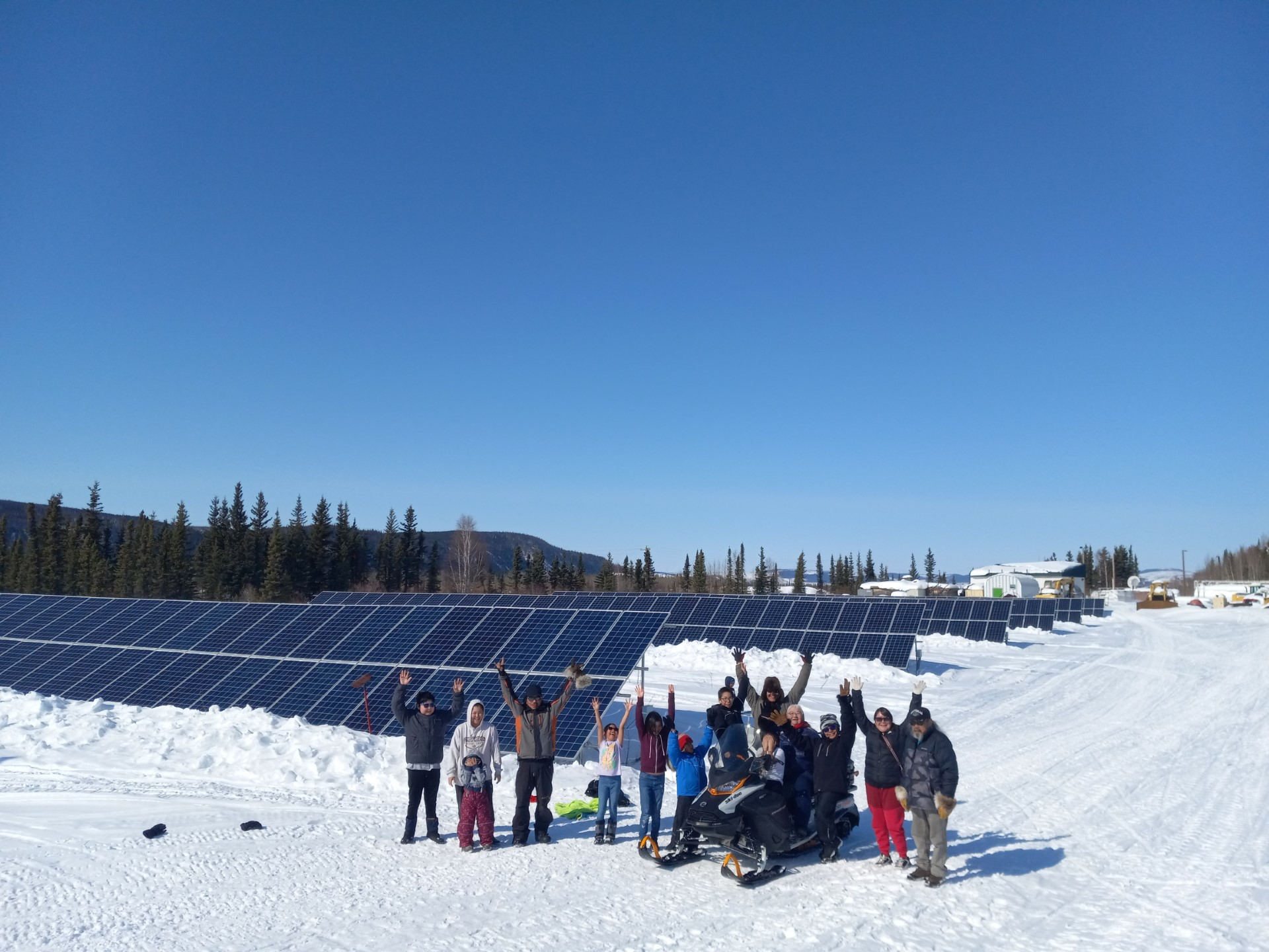 Residents of Hughes, Alaska next to solar installation (source: Eddie Dellamary)